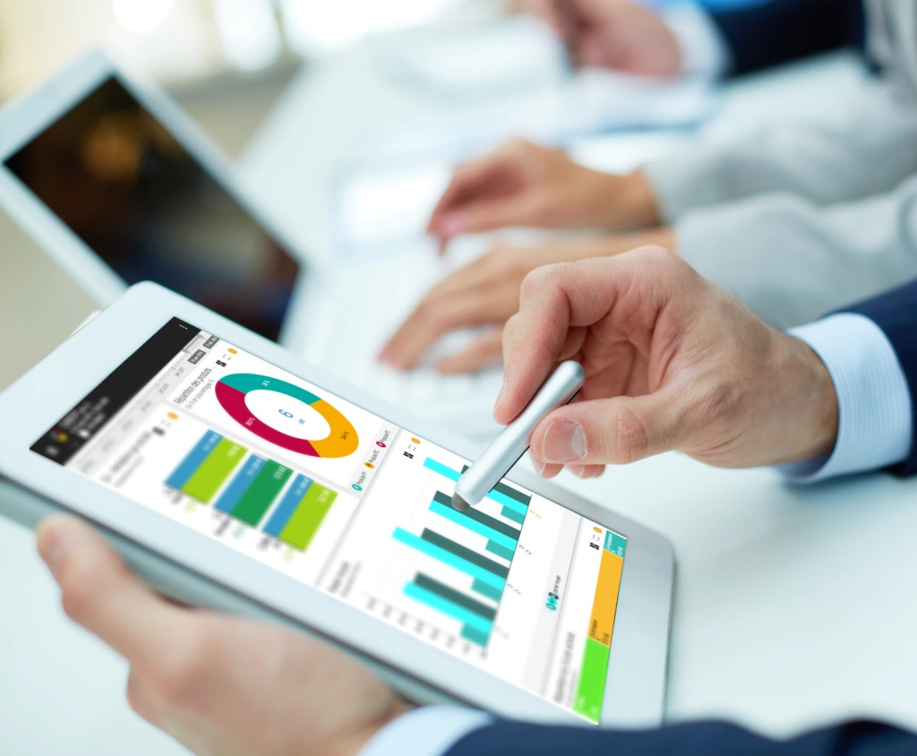 Personne utilisant une tablette affichant un tableau de bord interactif avec graphiques et indicateurs de performance.